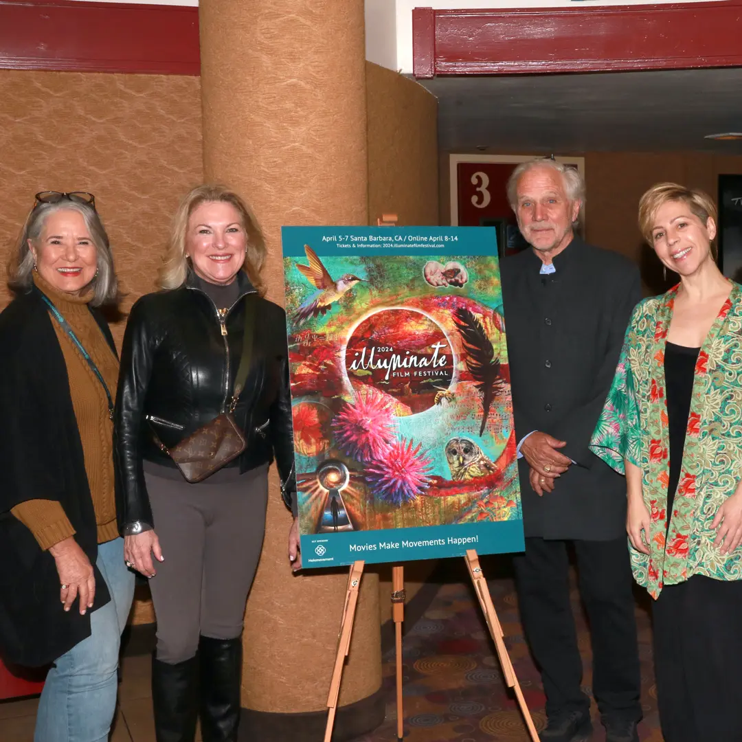 Festival attendees posed with the 2024 ILLUMINATE Film Festival poster, which features vibrant artwork with a hummingbird and nature motifs.